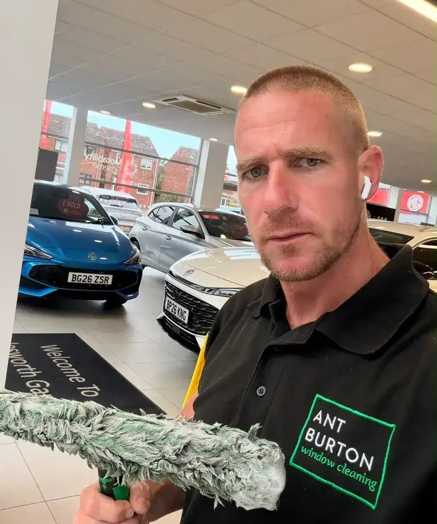 Ant Burton holding a filthy window cleaning applicator sleeve inside the Polesworth Garage MG showroom